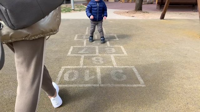 Mom On The Playground Jumping To Hopscotch With Her Son