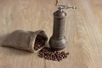 Coffee beans and old copper coffee grinder on the table