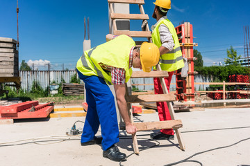 Two young blue-collar workers leaning a ladder © Kzenon