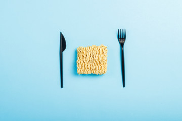 Asian instant noodles and plastic disposable dishes on a blue background. The concept of...