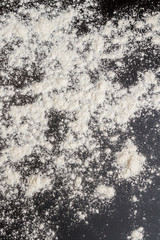 White flour is poured on a black table before cooking cookies