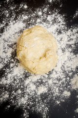 Raw dough is on the table with flour before cooking cottage cheese cookies