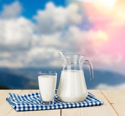 Glass of milk and jug on blurred background