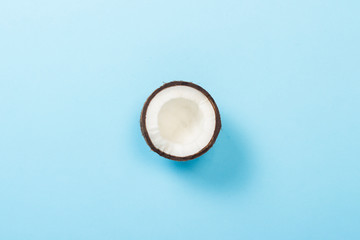 Half coconut on a blue background. Minimalism. Concept of tropics, healthy eating. Flat lay, top view.