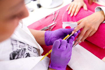 Fototapeta na wymiar Artificial nail enhancement being applied by the hands of an experienced manicure salon worker