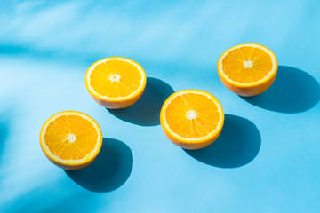 Oranges on a blue background under natural light with shadows. Hard light. Concept of diet, healthy eating, rest in the tropics, vacation and travel, vitamins.