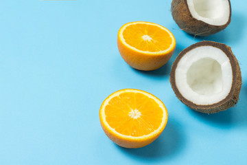 Obraz na płótnie Canvas Cut orange and coconut on a blue background. Concept of tropical fruits, vacation and travel, diet and weight loss.