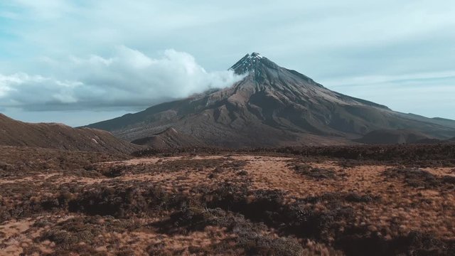 Dramatic drone aerial footage of Mount Taranaki Egmont National Park 4k flying backwards and panning down over 2 hikers