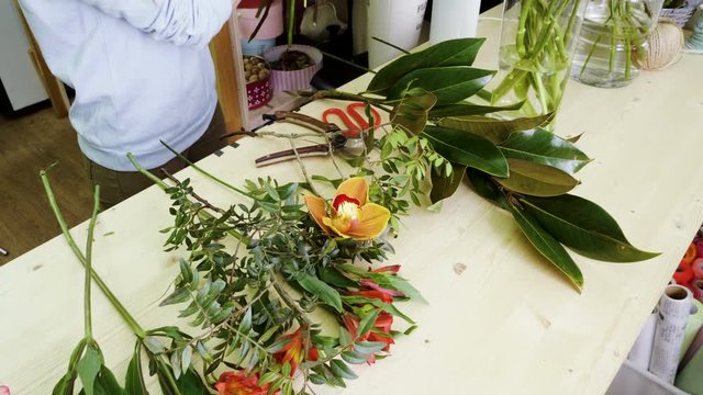Female florist in flower shop. Woman making a beautiful and stylish bouquet of fresh flowers in floral design studio. 4K