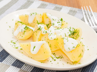 boiled potatoes with greens on a white plate garnish