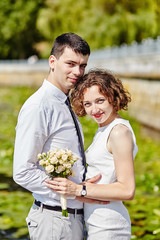 Portrait of young couple in love. Bride and groom hug in the park near a pond. People on a background of water lilies
