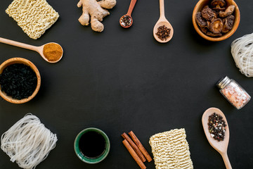 Chinese and Japanese food cooking with ginger, spices and noodles frame on black background top view space for text