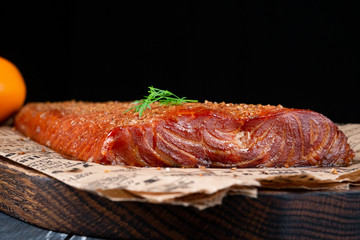 Smoked Fillet salmon fish with pepper and salt on wooden cutting board on dark background