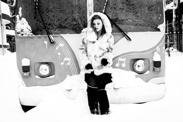 beautiful girl in a beige coat and hood stands in front of a trolley bus, black and white photo
