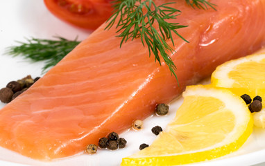 .A dish of a piece of red fish fillet with lemon and herbs