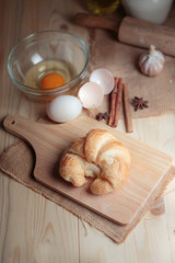 Croissant on wooden cut board on table wood and fabric select focus shallow depth of field