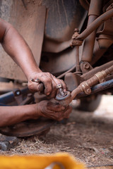 Hands of mechanic fixing wishbone control arm of the truck part to repair front wheel