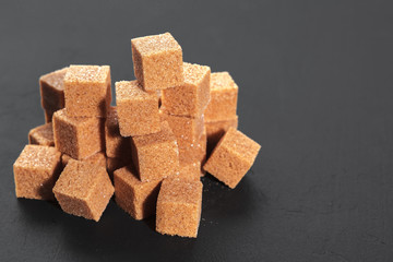 Natural brown sugar cubes on rough black background