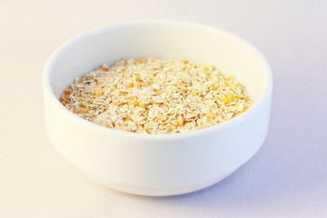 Oatmeal with yellow apricot pieces in a deep white bowl, a wooden spoon, a jar of milk.