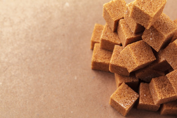 Brown cane sugar cubes on a light brown background