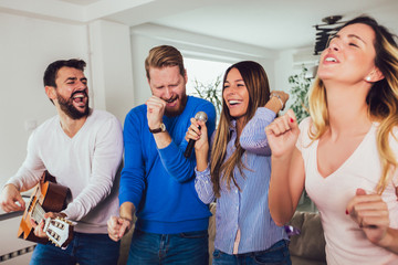 Group of friends playing karaoke at home. Concept about friendship, home entertainment and people
