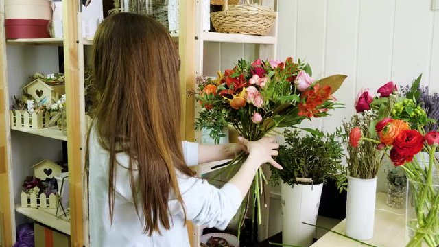 Female florist in flower shop. Woman making a beautiful and stylish bouquet of fresh flowers in floral design studio. 4K