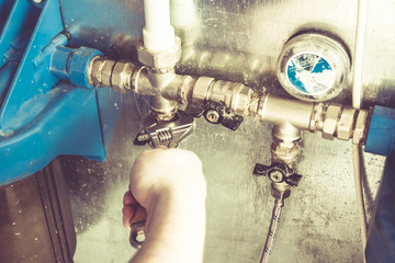 Man unscrews filter to water with adjustable wrench in basement