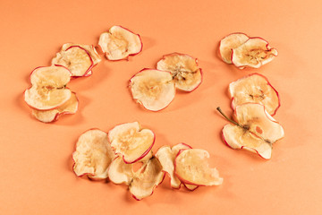 Apple chips are lying on coral background.