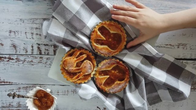 Childs hand takes an Easter cake tartlet fray from a plate close-up above