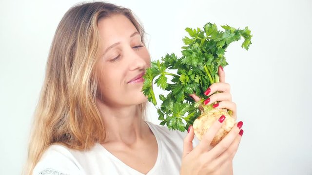 Young pretty woman holding fresh celery root