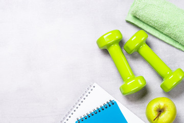 Dumbbells, measuring tape, water and apple top view.