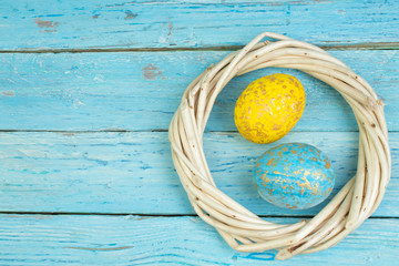Happy Easter.Colorful shiny eggs on wooden table background. wreath woven from the vines. Copy space for text. Top view.