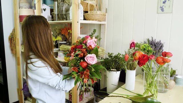 Female florist in flower shop. Woman making a beautiful and stylish bouquet of fresh flowers in floral design studio. 4K