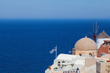 Santorini skyline with Greek flag, sea, blue sky and town. Greece landmark
