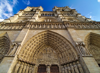 Notre Dame de Paris cathedral, France. Winter blue sky with some clouds. Close view, looking up.