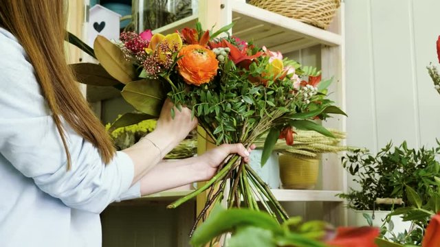 Female florist in flower shop. Woman making a beautiful and stylish bouquet of fresh flowers in floral design studio. 4K