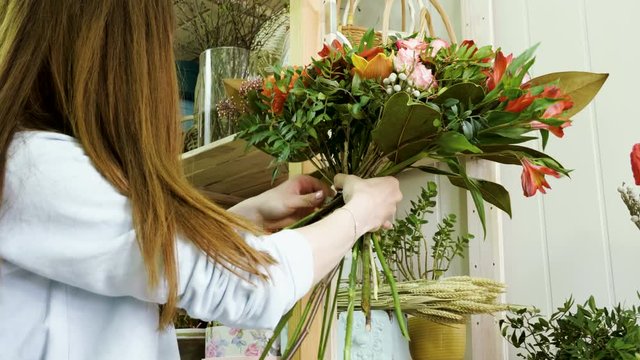 Female florist in flower shop. Woman making a beautiful and stylish bouquet of fresh flowers in floral design studio. 4K