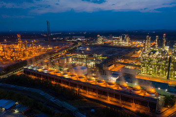 Fototapeta premium Aerial view. Oil refinery factory and oil storage tank at twilight and night. Petrochemical Industrial.