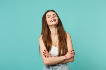 Portrait of laughing young woman in light casual clothes looking camera holding hands crossed isolated on blue turquoise wall background. People sincere emotions lifestyle concept. Mock up copy space.