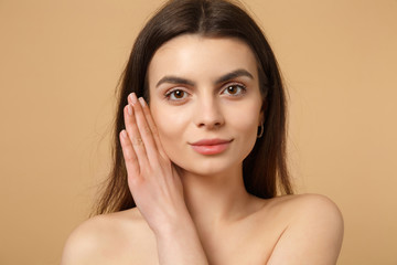Close up brunette half naked woman 20s with perfect skin, hand on cheek isolated on beige pastel wall background, studio portrait. Skin care healthcare cosmetic procedures concept. Mock up copy space.