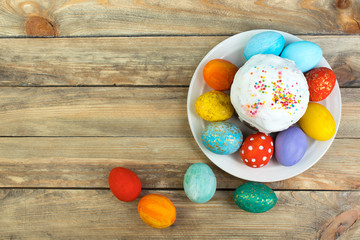 Happy Easter card. Colorful shiny easter eggs cake with white icing and sugar decor on the table decorated in rustic style. Copy space for text.