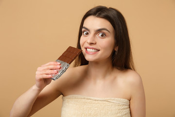 Close up half naked woman 20s with perfect skin, nude make up hold chocolate bar isolated on beige...