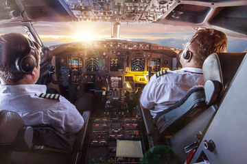 Pilots in the cockpit during a flight with commercial airplane. - obrazy, fototapety, plakaty
