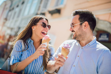 Happy couple having date and eating ice cream after shopping