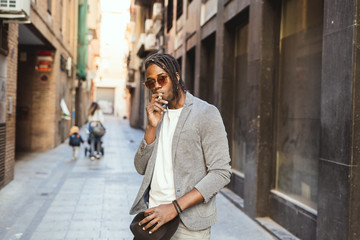 Fototapeta na wymiar African-American man smoking a cigar in the street. Black guy style