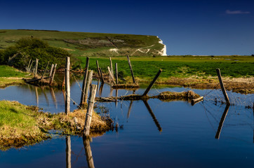 Posts in water with hill in background