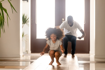 Happy African American man playing funny game with daughter at home