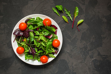 salad with tomato, lettuce, arugula, spinach and other leaves. food background. top