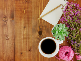 Flat lay,top view grey wooden desk with stationery including notebook and pencil with a cup of coffee,flowers and copy space