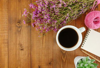 Flat lay,top view grey wooden desk with stationery including notebook and pencil with a cup of coffee,flowers and copy space